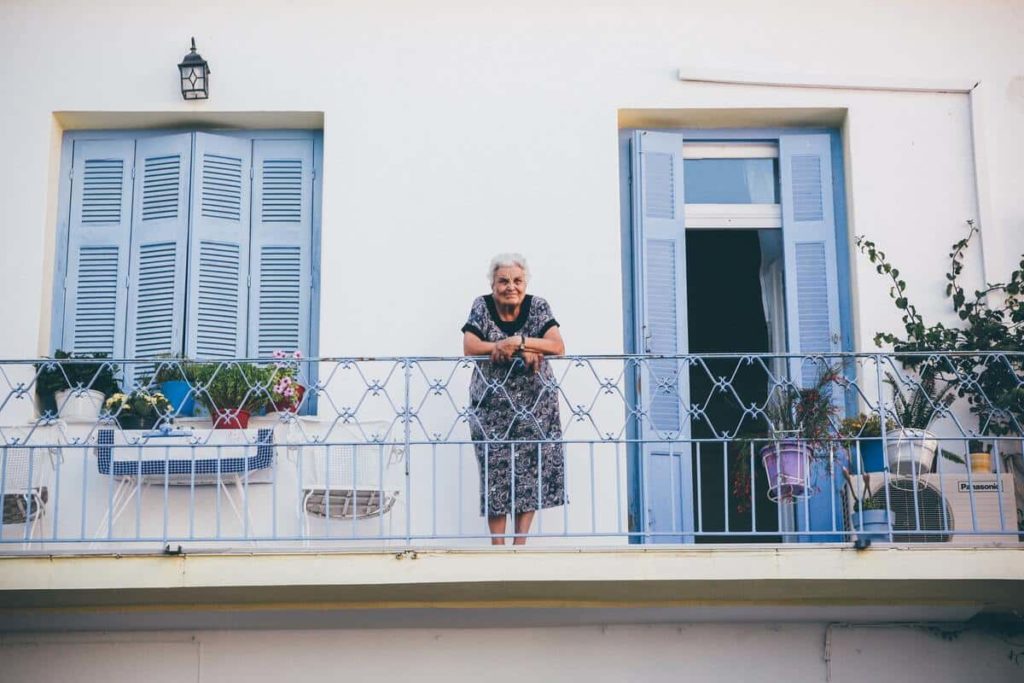 Personne âgée au balcon de son appartement