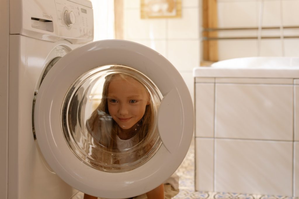 Enfant derrière la porte d'un lave linge