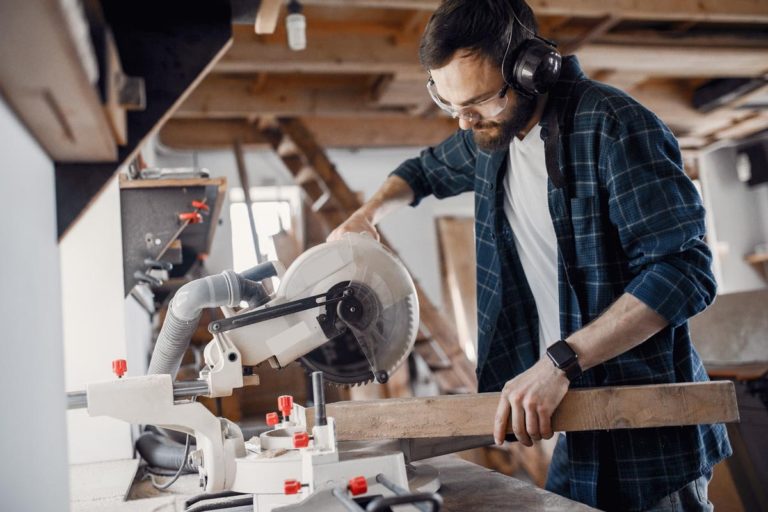 homme travaille bois avec scie à onglet atelier