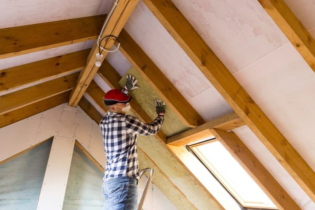 ouvrier isolant les combles d'une maison