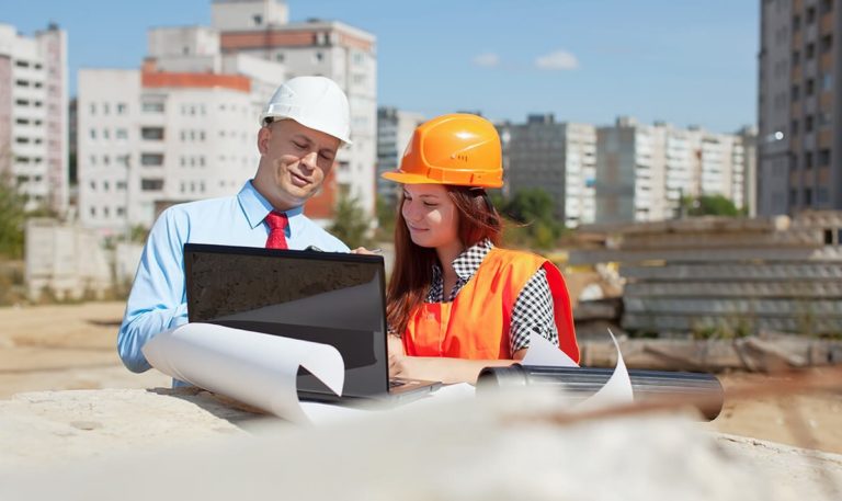 deux ouvriers sur chantier avec casque et devant ordinateur