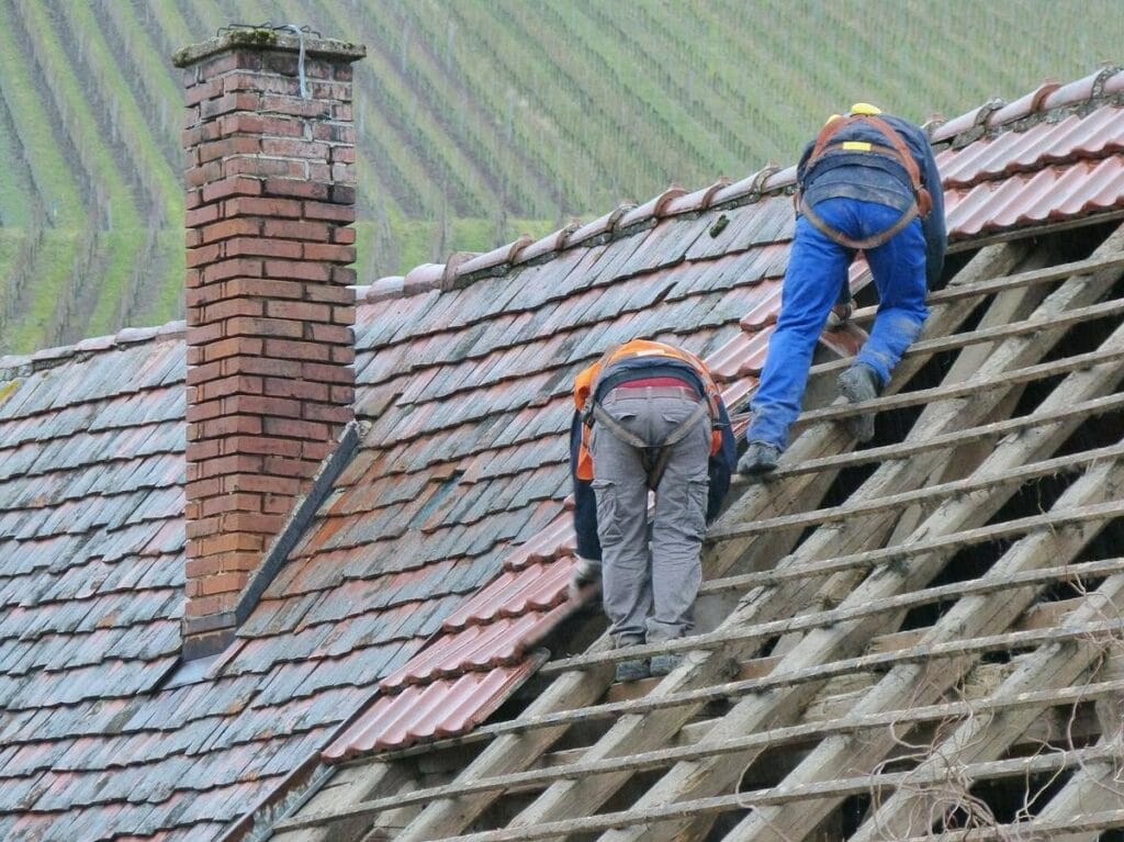 renovation toiture de maison ancienne avec ouvrier sur toit
